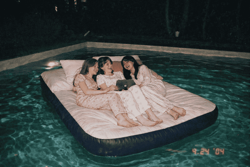 Imagem de amigas no colchão inflavel em cima da piscina como uma das coisas para fazer em casa com as amigas nas férias