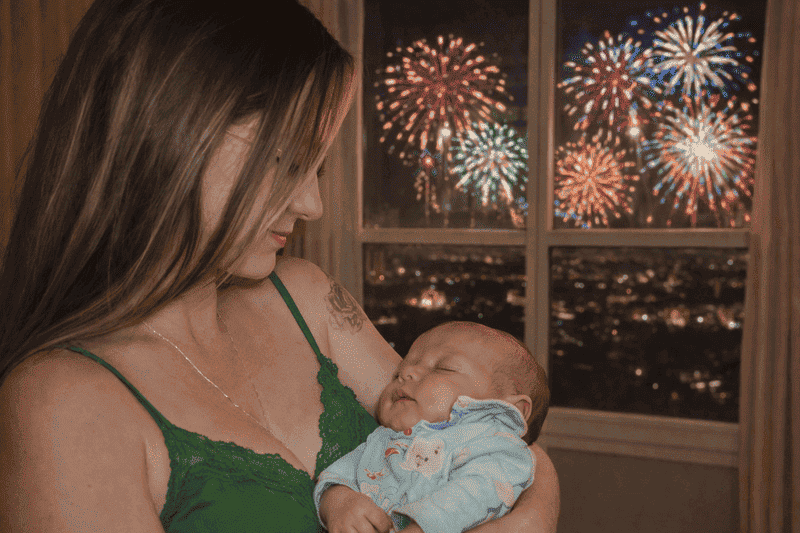 Imagem de mãe segurando bebê calmo e usando dicas de como proteger o bebê do barulho dos fogos de artifício